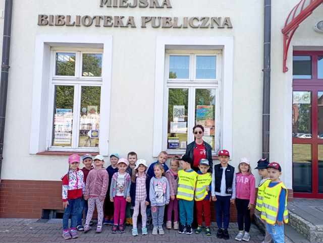 przedszkolaki stoja pod biblioteka