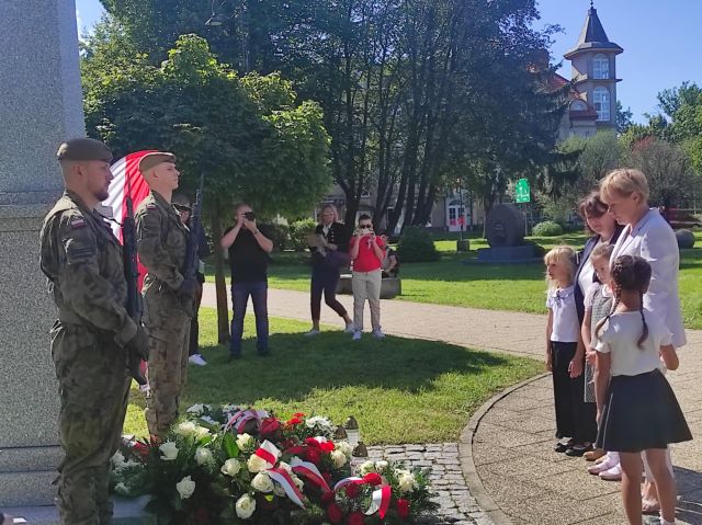 dyrektor z dziecmi przed pomnikim