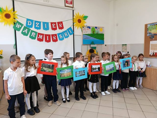 dzieci stoja z kolorowymi kartkami